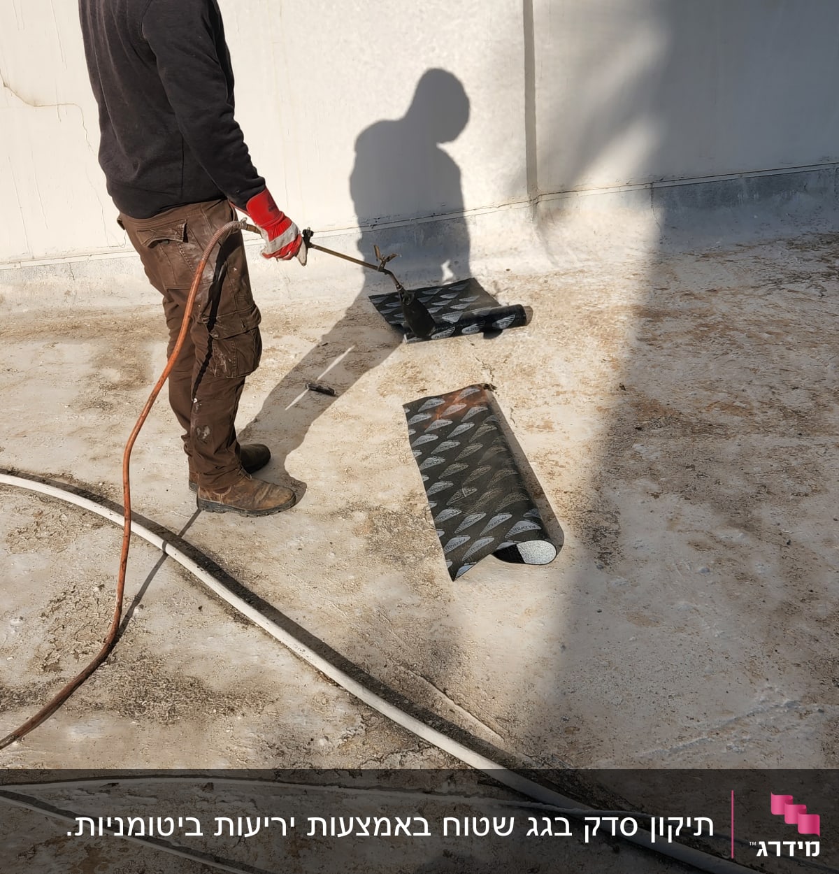 אדם עם מבער מחמם יריעות איטום על גג